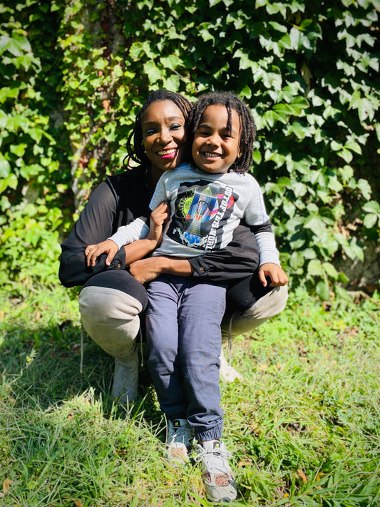 African American mother and son photographed  infront of greenery wall